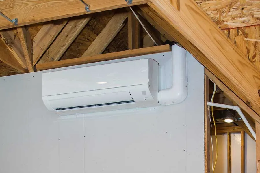 Wall-mounted ductless mini split system being prepared for repair inside an unfinished interior space